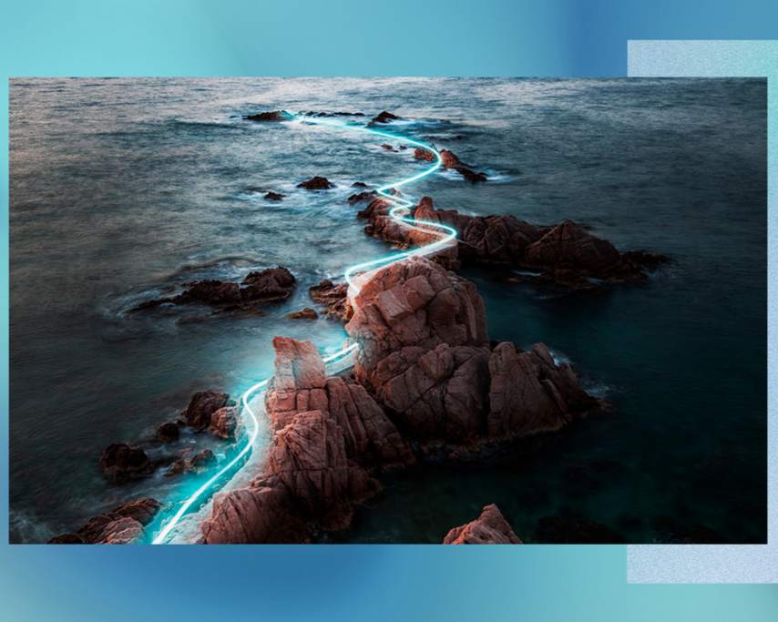 Imagen de unas rocas en el mar con una raya de luz que le atraviesa
