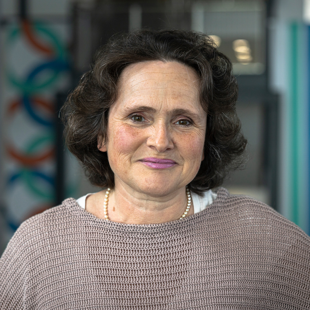 Portrait of a woman with brown curly hair looking straight at the camera.
